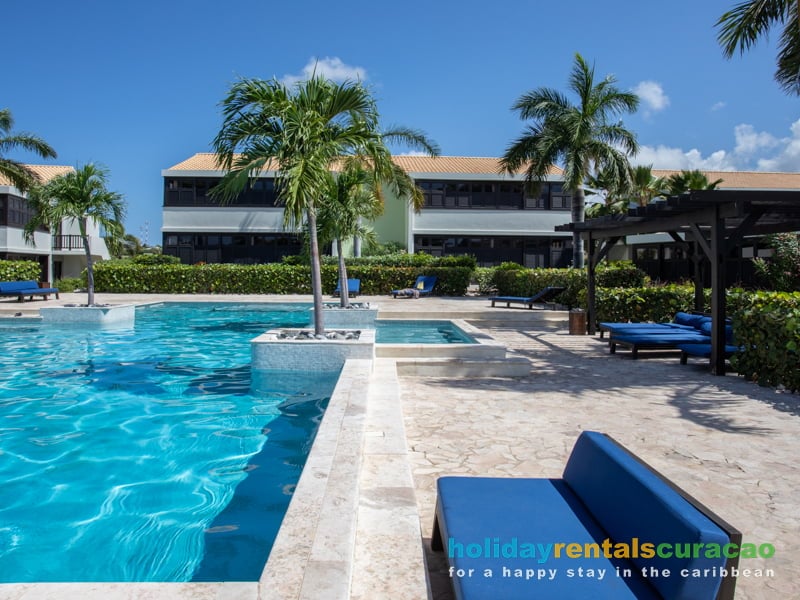 Tropisch zwembad met ligstoelen en loungebanken blue bay Curacao